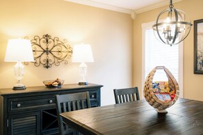 Un coin repas avec une table en bois foncé, deux lampes, un élément décoratif mural et un lustre.