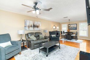 Un salon spacieux comprenant un canapé, des fauteuils, une table basse et un coin repas avec une table et des chaises.