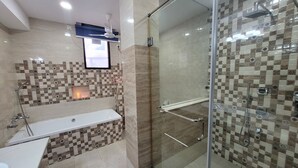Um banheiro com chuveiro em box de vidro, banheira branca e parede revestida com um padrão quadriculado.