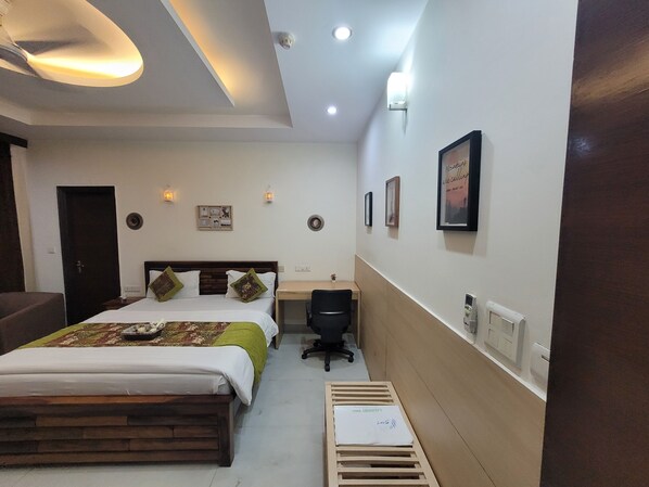 A hotel room with a bed, desk, chair, and a small table.