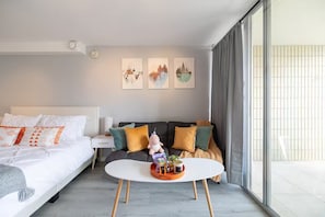 A modern hotel room with a bed, a sofa, a small table, and a large window. - Condo with Canal View in Center Waikiki Near Beach (Honolulu)