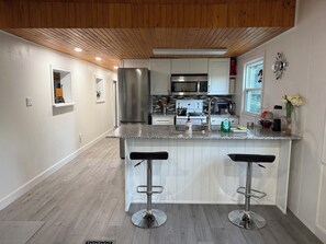 Una cocina moderna con una isla central, electrodomésticos de acero inoxidable y techo de madera.