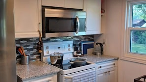 A kitchen with white cabinets, a microwave, a stove, and a coffee maker.