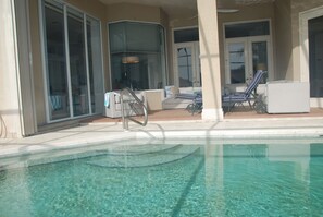A pool area with clear water, a lounge chair, and a small table. - Fabulous 3-bedroom house with AC & heated private pool in sunny Naples Florida (Naples)