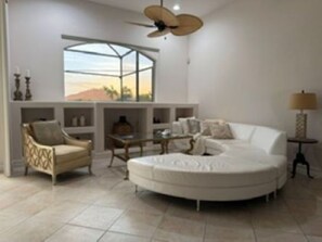 Ein modernes Wohnzimmer mit einem weißen Sofa, einem runden Couchtisch und einem Deckenventilator.