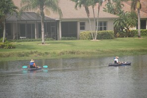 Two people kayaking on a calm body of water with a building and palm trees in the background. - Fabulous 3-bedroom house with AC & heated private pool in sunny Naples Florida (Naples)