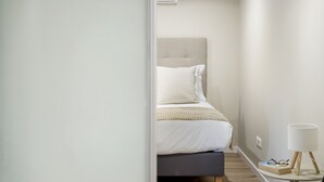 A bedroom with a bed, bedside table, and a lamp. - Oceanea Apartment by Homie (Santa Cruz)
