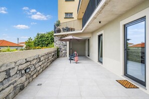 Eine moderne Außenpatio mit einer Steinmauer, einer Sitzecke mit Stühlen und einem großen Sonnenschirm.