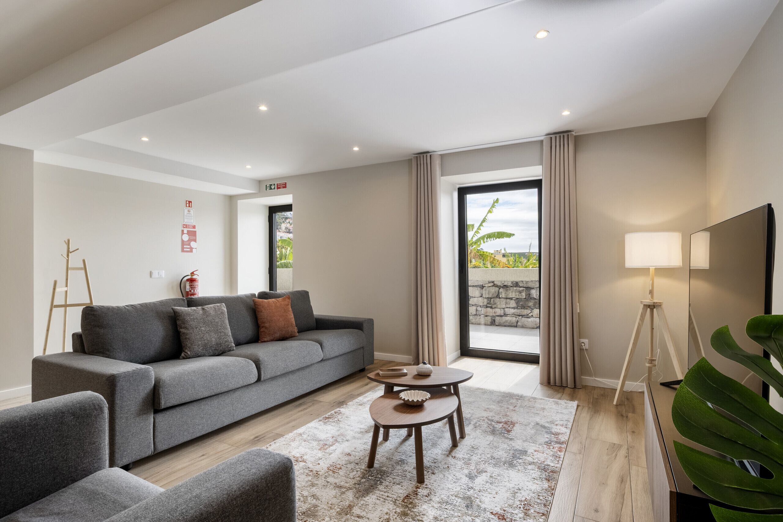 Un salon moderne avec un canapé gris, une table basse et un meuble pour la télévision.