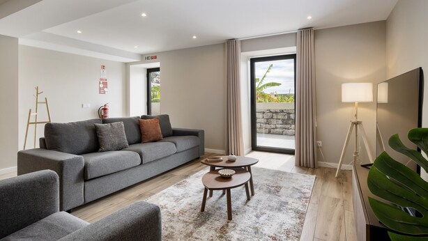 A modern living room with a grey sofa, a coffee table, and a TV stand. - Oceanea Apartment by Homie (Santa Cruz)