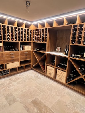 A wine cellar with wooden shelves and drawers, illuminated by overhead lighting. - Provençal villa 4bd, pool, sauna, gym, wine cellar — 5min to Valbonne (Valbonne)