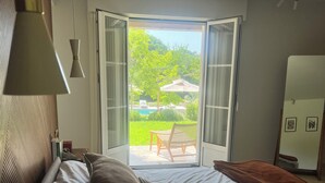 Et hotelværelse med en seng, udsigt til det fri og en dør, der fører til en balkon.