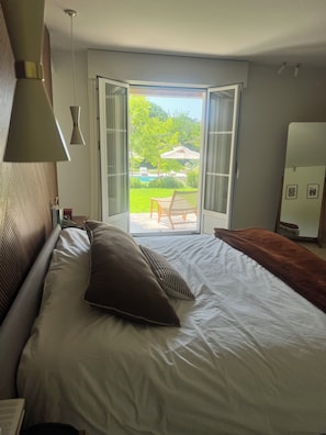 A hotel room with a bed, a view of the outdoors, and a door leading to a balcony. - Provençal villa 4bd, pool, sauna, gym, wine cellar — 5min to Valbonne (Valbonne)