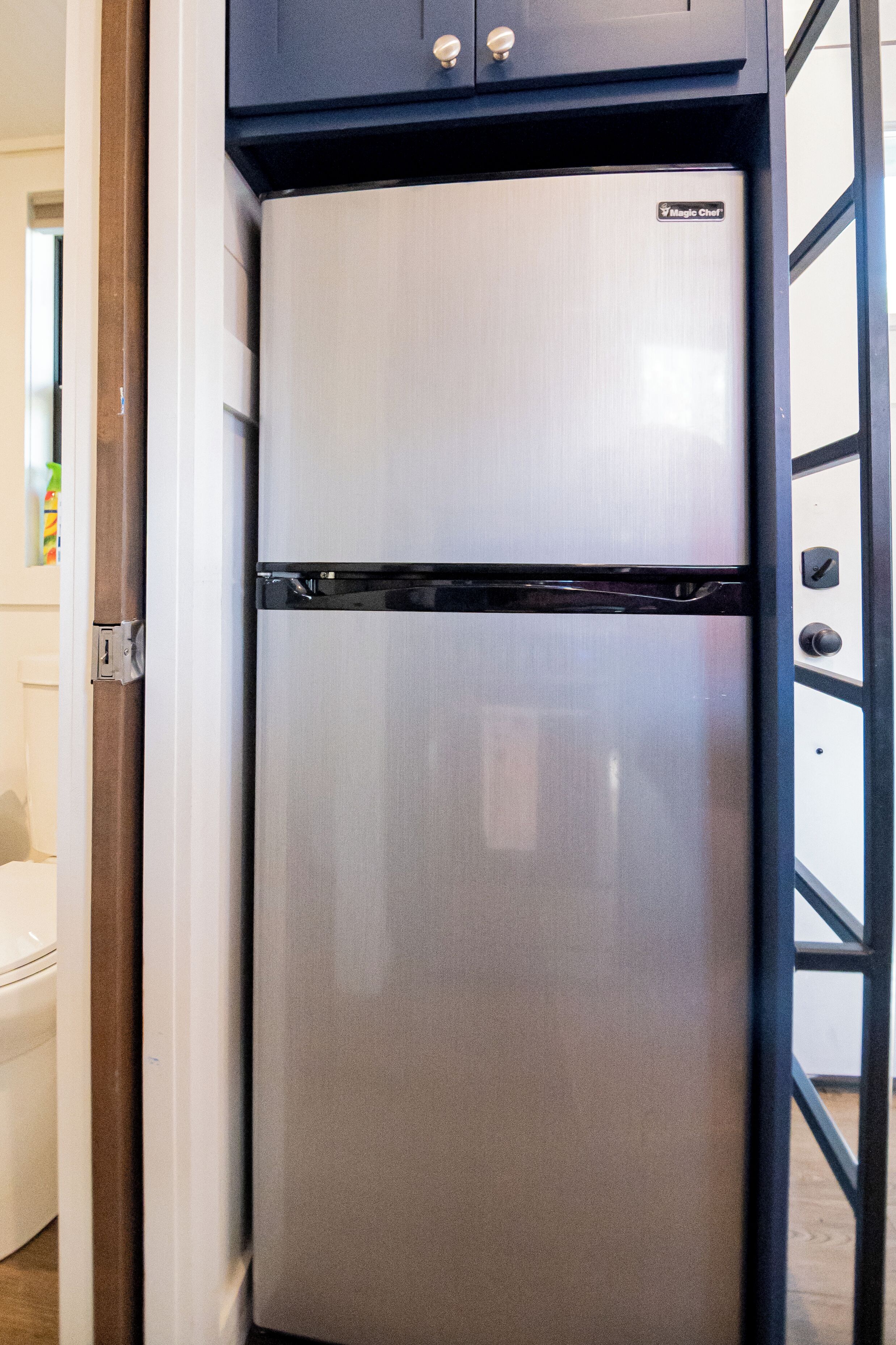 A stainless steel refrigerator with a black top and a logo on the front.