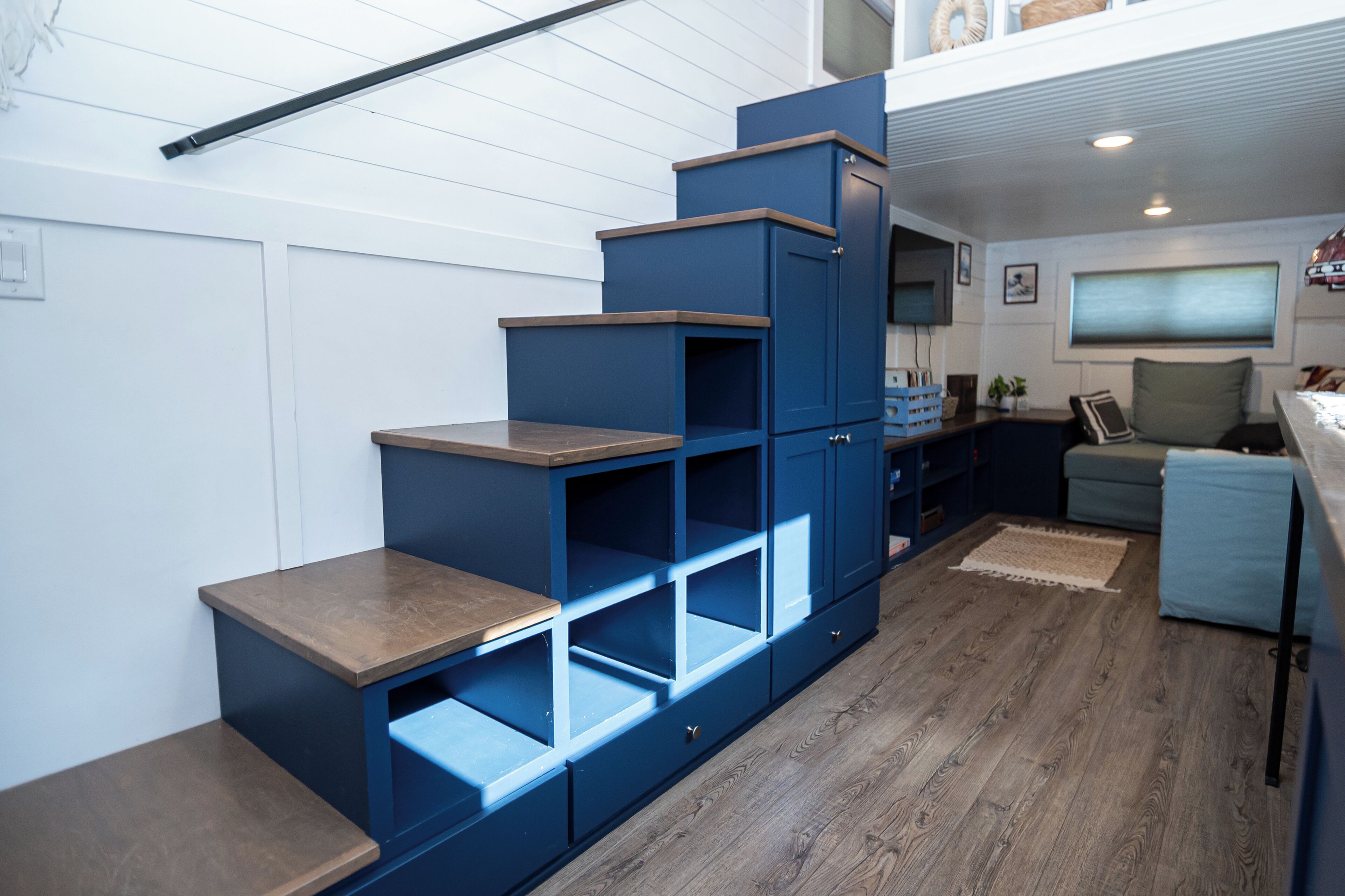 A compact living space with a built-in shelving unit, a small seating area, and a kitchenette.