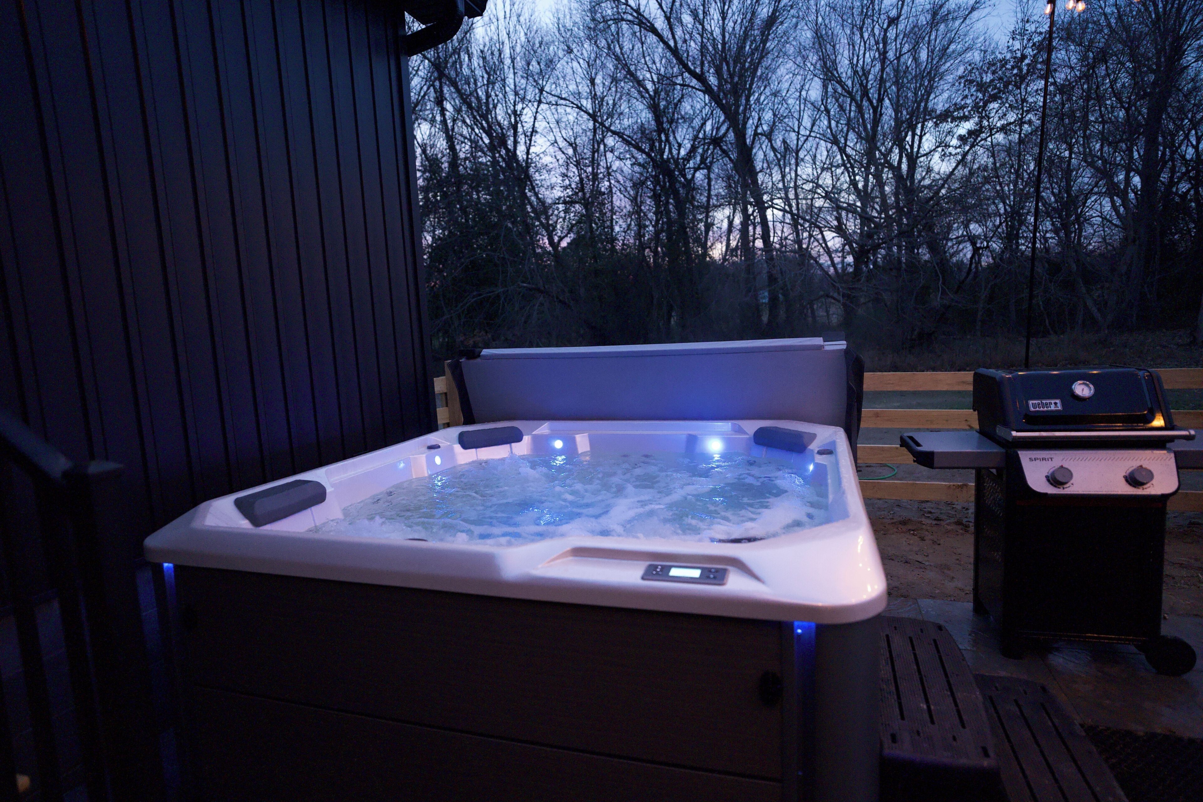 Una vasca idromassaggio con pannello di controllo digitale, un barbecue e un pontile in legno.