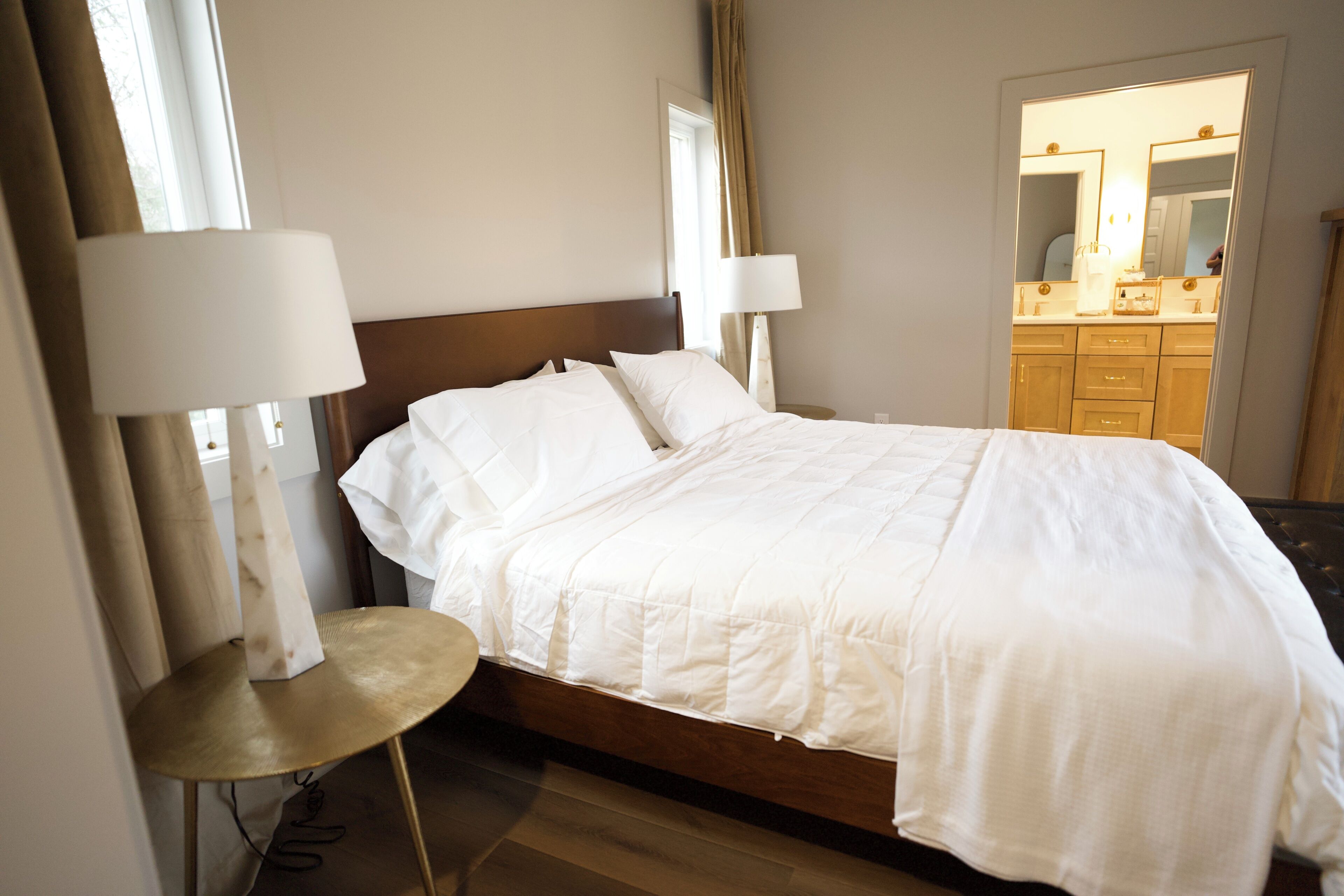 Une chambre d’hôtel avec un lit, deux lampes de chevet, une table ronde et une salle de bain visible à travers une porte ouverte.