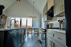 Una cocina moderna con una isla central, sillas de madera y vistas a través de las ventanas.