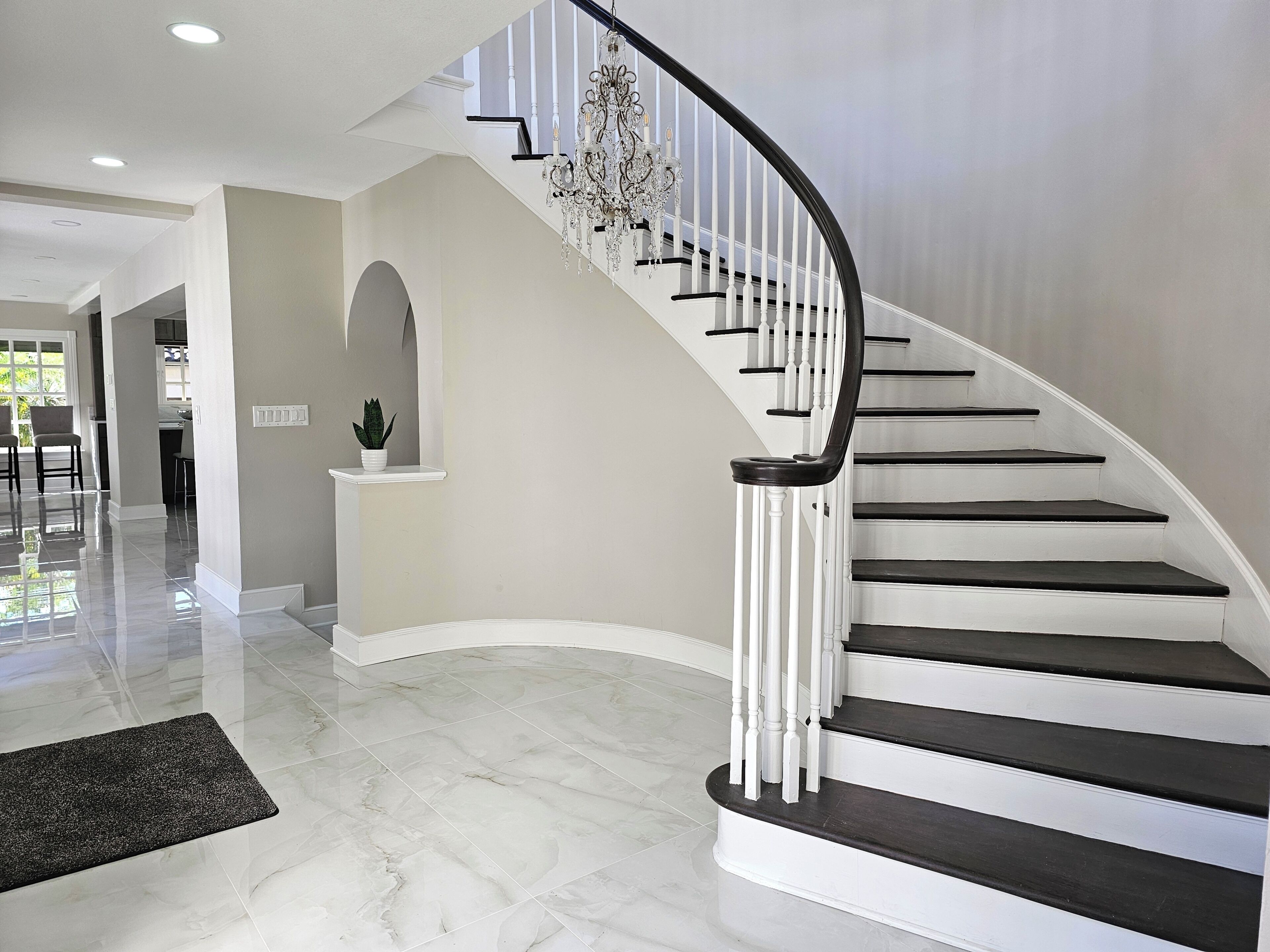 A curved staircase with white railings and dark steps, leading to an upper floor.