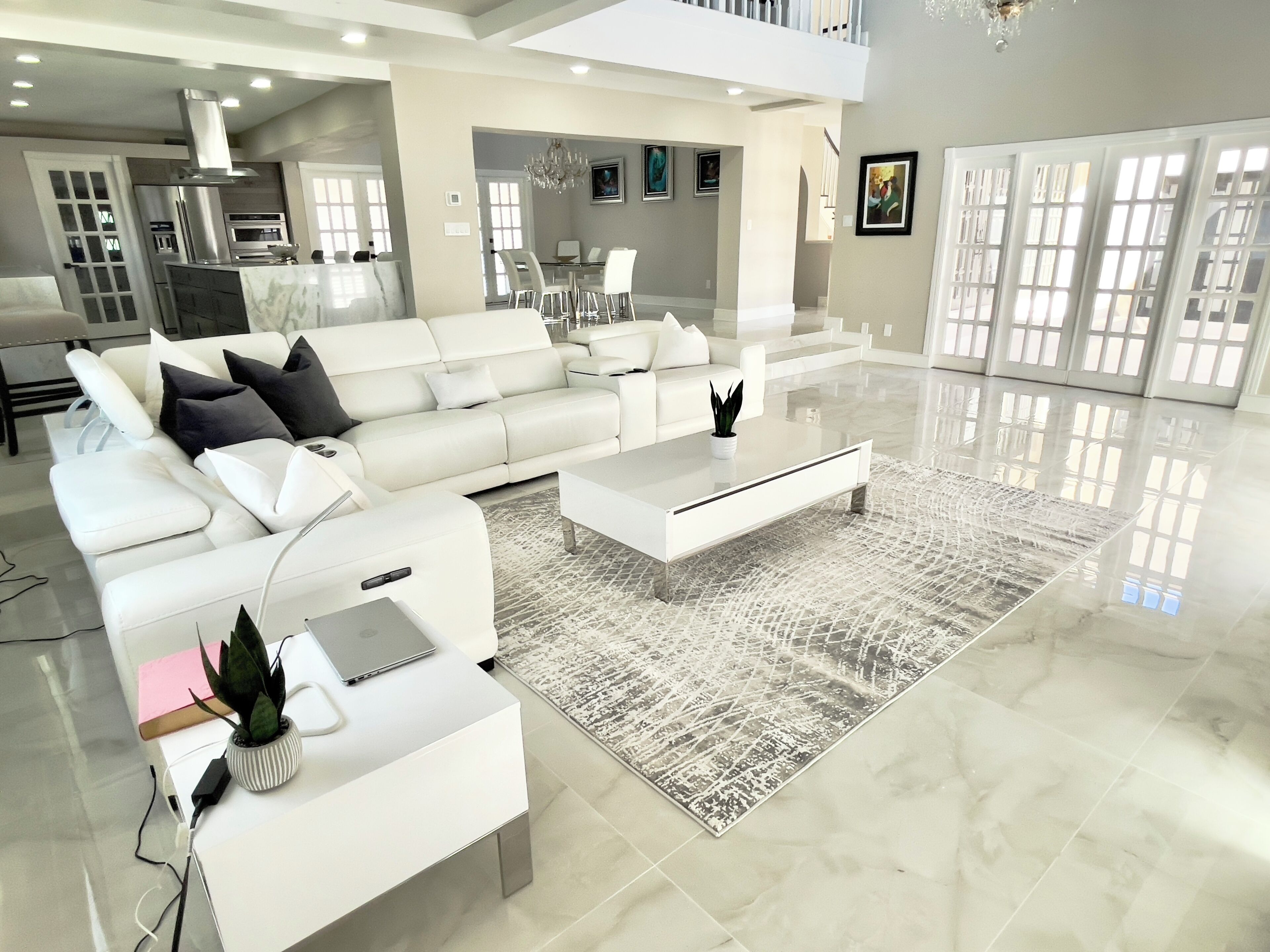 A modern living room with a white sofa, coffee table, and a dining area with chairs.