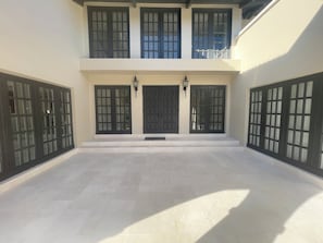 A building with a central entrance, two doors with glass panels, and a tiled courtyard. - Lovely 4-bedroom house with AC in beautiful Tampa (Tampa)