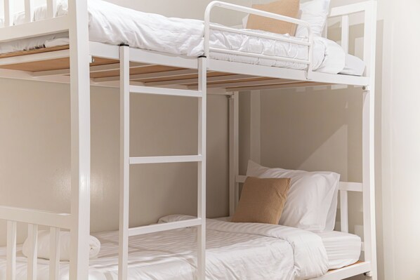 Un lit superposé avec une literie blanche et une tête de lit en bois.