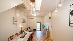 A modern living space with a dining area, a sofa, a TV, and a plant. - Siam Place Family House Near Khaosan 8 Guests (Bangkok)