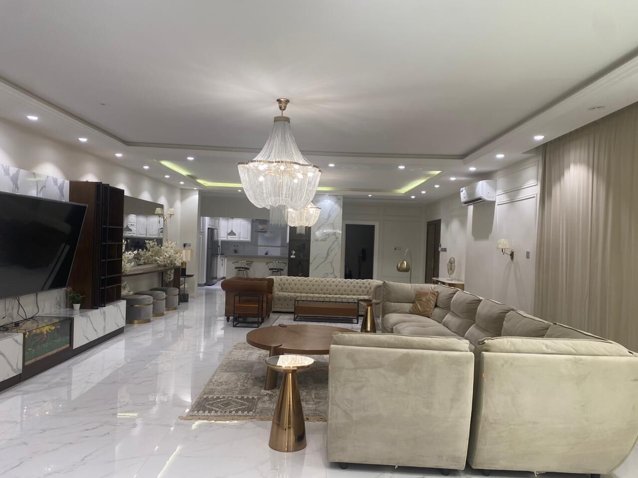 A modern living room with a large sectional sofa, a coffee table, and a television.