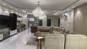 Una sala moderna con un amplio sofá modular, una mesa de centro y un televisor.