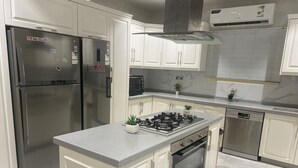 Una cocina moderna con electrodomésticos de acero inoxidable, una isla central y armarios blancos.