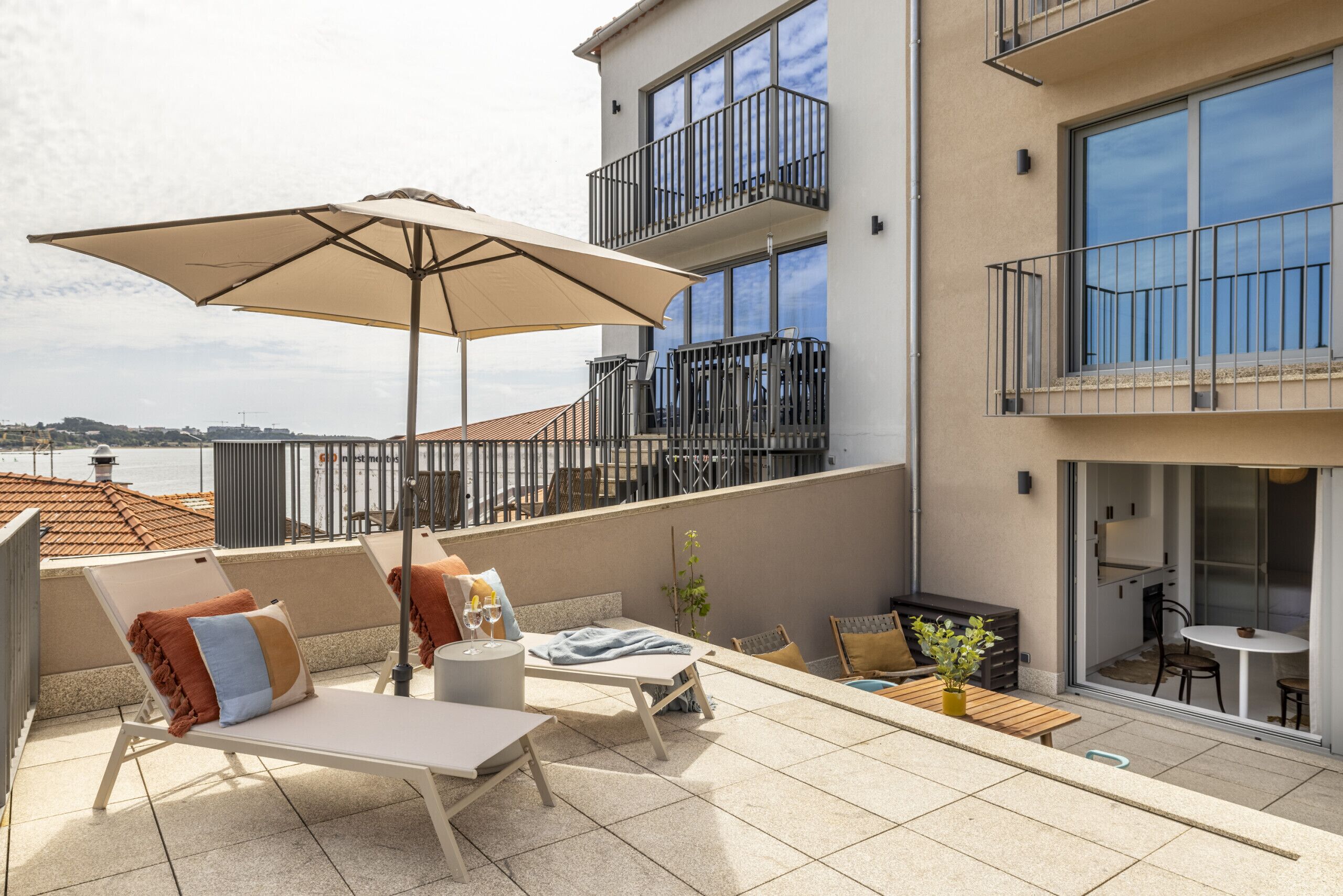 Une terrasse sur le toit, avec des chaises longues, une table et un grand parasol.