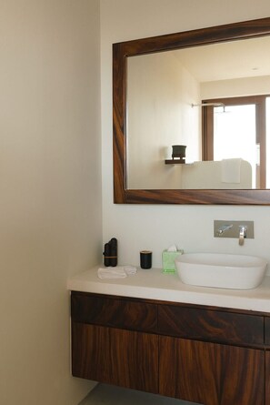 Une salle de bain avec un meuble-lavabo en bois, un lavabo blanc, un miroir et un porte-serviettes.