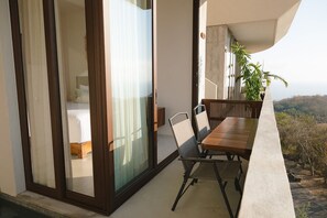 Un balcon avec une table et des chaises pour prendre les repas, une porte-fenêtre coulissante et une vue sur le paysage.