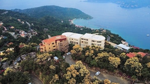 A coastal building complex with multiple structures, surrounded by lush greenery and a clear view of the sea. - Studio Villa at Cerro del Vigia (Zihuatanejo)