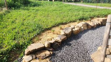 A pathway with a stone border leading to a grassy area with trees.