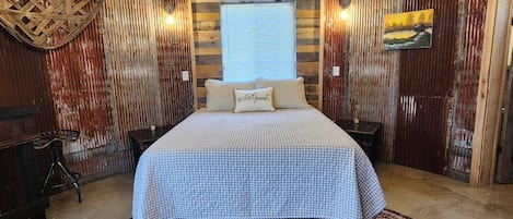 A room with a large bed, a wooden ceiling, a window, and a wall-mounted air conditioner.
