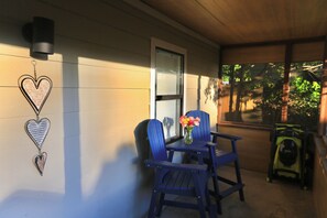 A porch with two blue chairs, a small table, and a vase with flowers. There are heart-shaped decorations on the wall. - Private & Pet-Friendly Guesthouse Near Marietta Square w/ Fenced Yard + King Bed (Marietta)