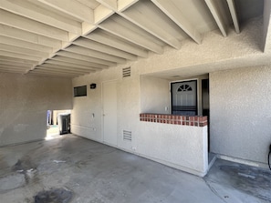 An interior corridor with a concrete floor, a door with a window, and a small brick ledge. - Luxury Living in Palm Desert! 2 Bed/2 Bath with a West Facing Patio (Palm Desert)