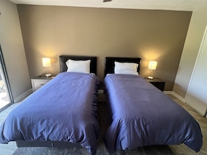 A hotel room with two single beds, each with a headboard, bedside tables, and lamps. - Luxury Living in Palm Desert! 2 Bed/2 Bath with a West Facing Patio (Palm Desert)