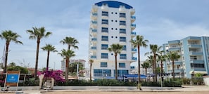 A multi-story hotel with balconies, palm trees, and a sign indicating a swimming pool area. - Mediterranean Resort Hotel (Silifke)