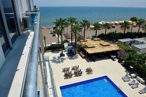 Un área de piscina con sillones de descanso y vista a la playa.