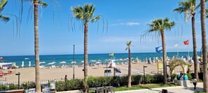A beach with palm trees, umbrellas, and a clear blue sky. - Mediterranean Resort Hotel (Silifke)