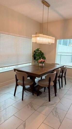 A dining area with a rectangular table, six chairs, a hanging light fixture, and a potted plant. - 5 BD / 4 BA / Champions Gate (444 OC) (Kissimmee)