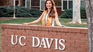 A person standing in front of a brick wall with the letters 'UC DAVIS' on it.