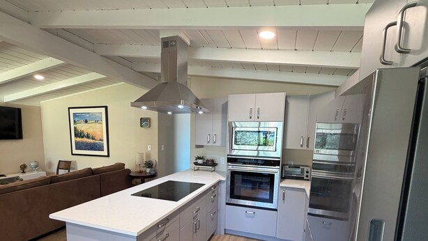 A modern kitchen with a central island, built-in oven, microwave, and stainless steel appliances.
