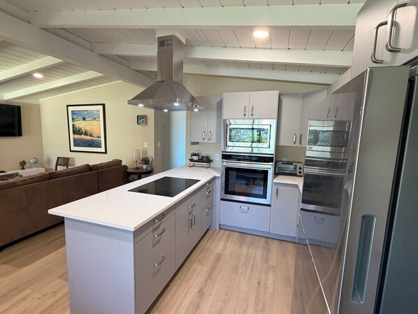 A modern kitchen with a central island, built-in oven, microwave, and stainless steel appliances.