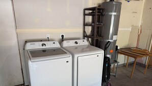 A laundry room with two white front-loading washers and a metal shelving unit.