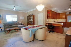 A living room with a sofa, ottoman, and a dining table with a colorful table runner. - 1-BDR condo with AC • walk to beach music dining •Private garden • Las Tunas (Todos Santos)