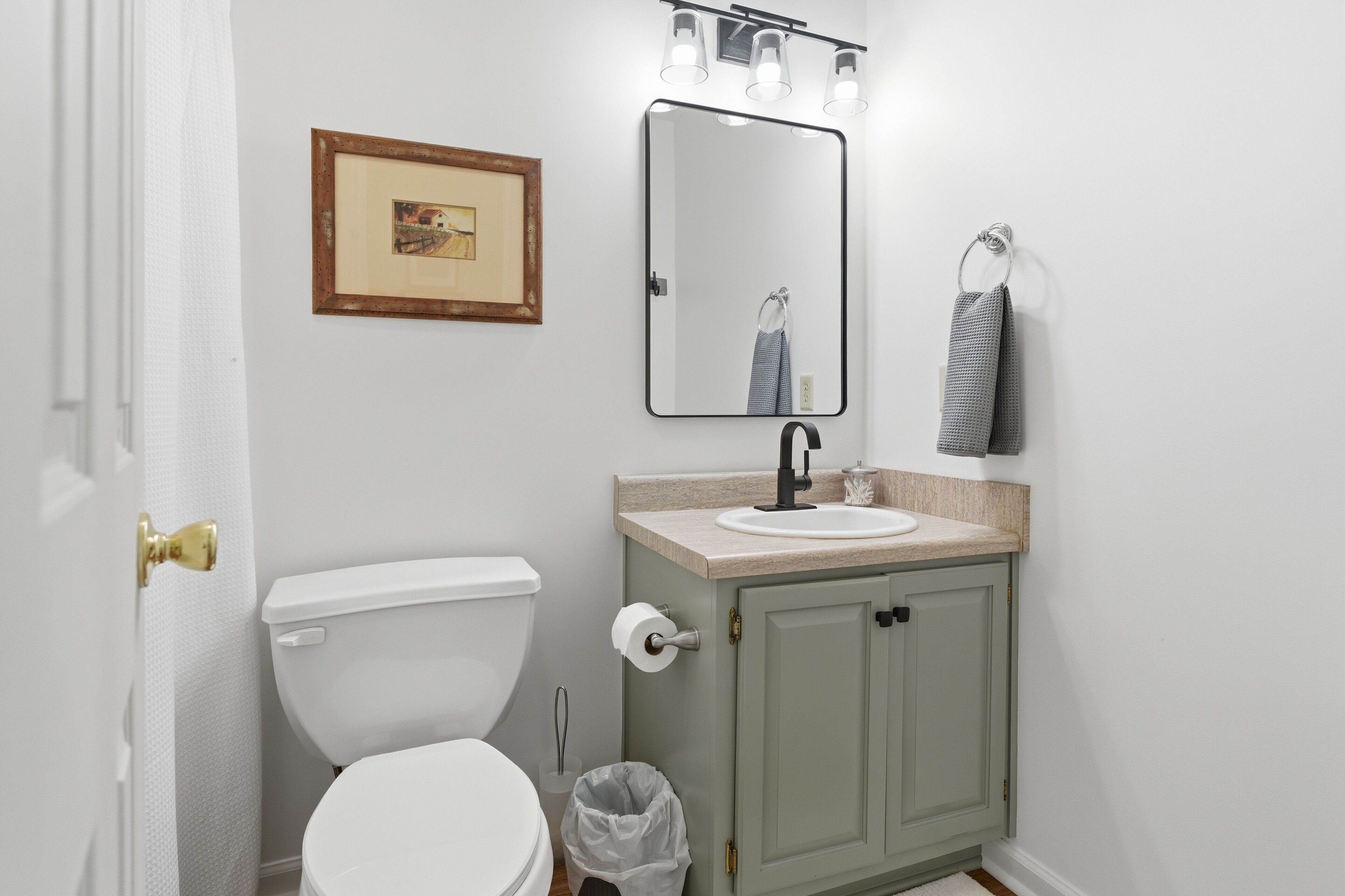 Ein Badezimmer mit Toilette, Waschbecken, Spiegel und Handtuchhalter.