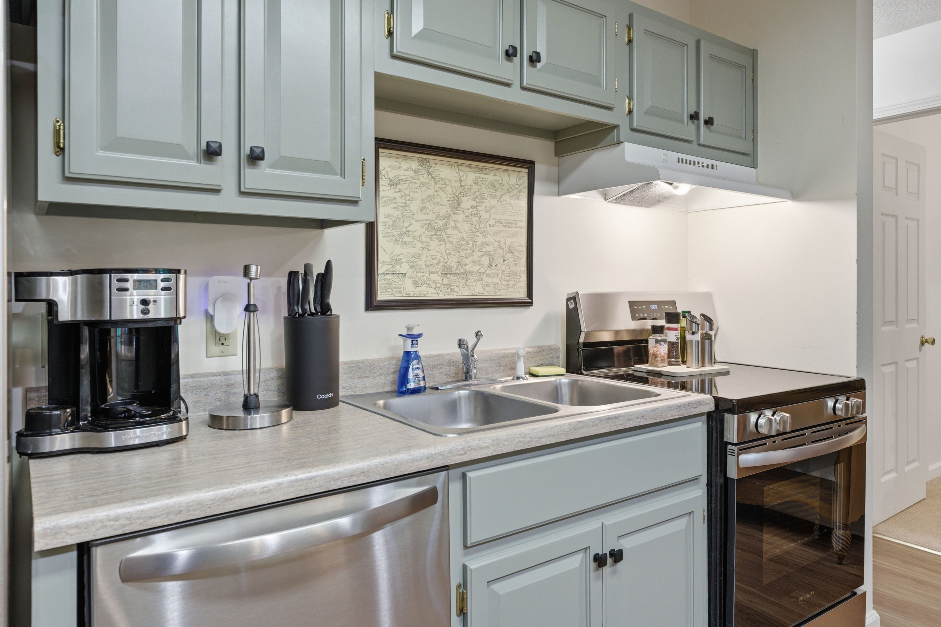 A kitchen with stainless steel appliances, a coffee maker, a sink, and a stove.